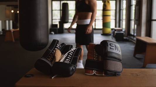 Two pairs of boxing gloves side by side on a gym bench, one lace-up and one velcro