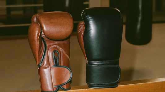 Side by side comparison of brown leather boxing gloves and black synthetic boxing gloves in a gym